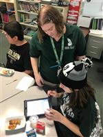 Standing teacher with seated student communicating with communication app on iPad 