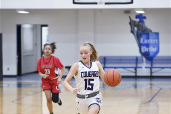 Number fifteen on the Girls Cougar Basketball team dribbling the ball