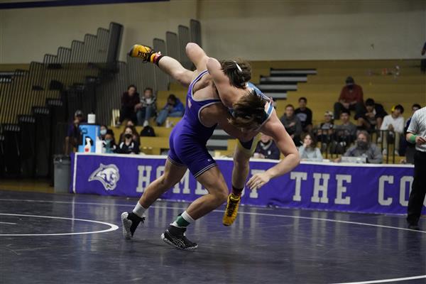 Two boys on the wrestling teams fighting, the Cougar player is slam dunkin the other player into the ground.
