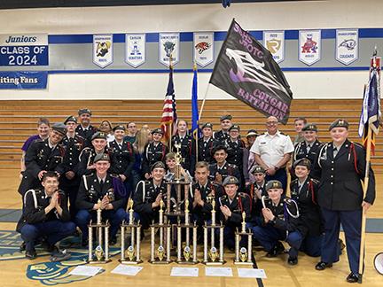 Spanish Springs JROTC posing next to trophies at Mcqueen highschool.