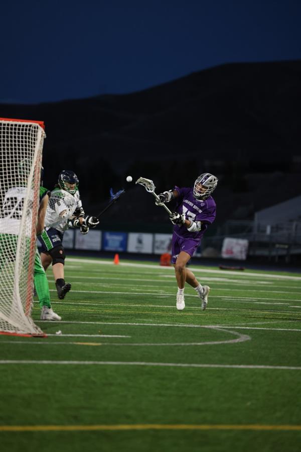 A Spanish Springs Boys Lacrosse player throwing the ball into the goal.