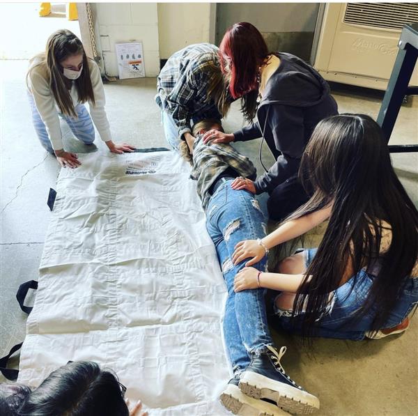 Sports Med students rolling a body onto a stretcher